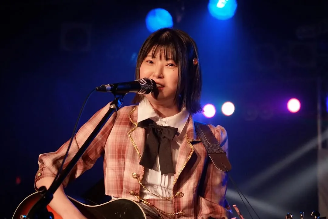 ステージでギターを弾きながら歌う小松みゆ